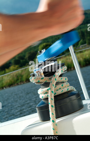 crew member turning winch on yacht Stock Photo