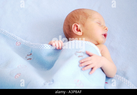 newborn baby sleeping on blue blanket Stock Photo