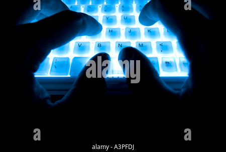 hands typing on blue backlit keyboard Stock Photo