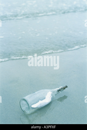 Message in a bottle washed up on beach Stock Photo