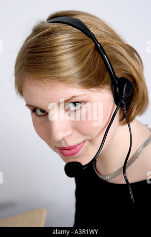 Young attractive woman answering calls on a headphone Stock Photo