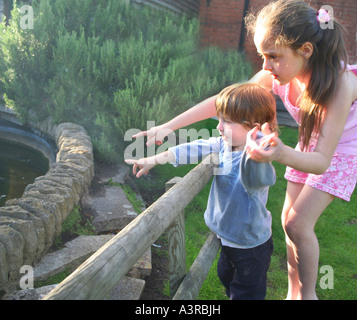 brother and sister pointing at a pond Stock Photo