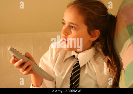 child watching TV holding a remote control Stock Photo