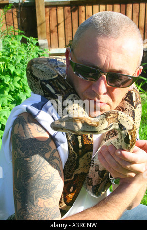 tough guy with tattoos handling a pet snake Stock Photo