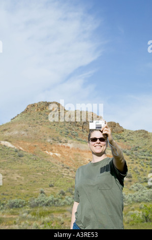 Woman 34yrs taking picture of herself with a digital camera Stock Photo