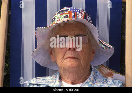 Sleep sleeping Older woman asleep sunbathing in a deckchair wearing a sun bonnet while on holiday Eastbourne Sussex 1990s UK HOMER SYKES Stock Photo