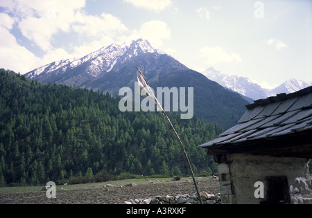 View in Chitkul Village of a typical mountain hut over some ploughed fields towards the Kinnaur mountain range Stock Photo