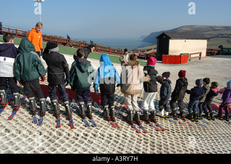 children lined up for skiing lesson on dry artificial ski slope at the Urdd Centre  Llangranog Ceredigion west wales UK Stock Photo