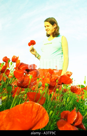 young woman standing in field of poppy flowers Stock Photo