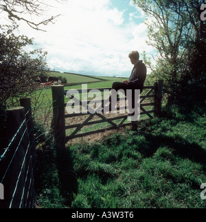 A farmer overlooks his wheat crop leaning on a field gate Stock Photo