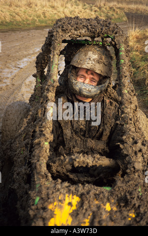 man driving muddy trak buggy covered in mud after race uk Stock Photo