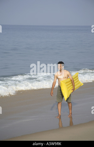 man on beach with floating air bed Stock Photo