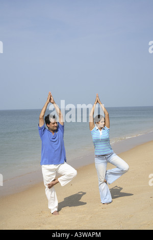 Couple doing standing yogic exercise on the beach Stock Photo