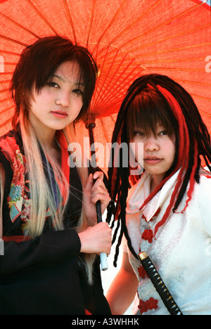 Cos-play teenagers under traditional red wagasa umbrella, Jingubashi bridge, Harajuku, Tokyo, Japan Stock Photo