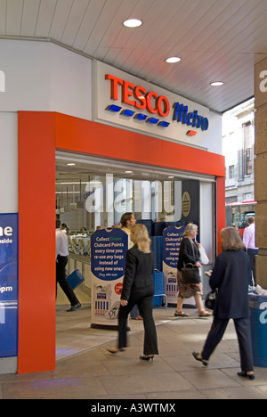 People shoppers walking in & out of busy Tesco Metro supermarket food & drink grocery retail business & convenience store City of London England UK Stock Photo