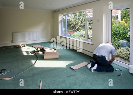 Home improvement makeover to living room with decorations complete & carpet fitter working on new floor covering after new windows & door England UK Stock Photo