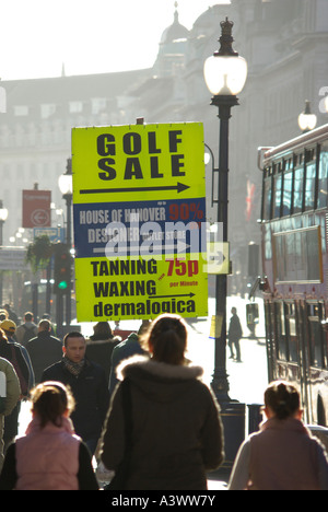 Pavement busy with shoppers man standing holding portable advertising panel promoting side turning shops Stock Photo