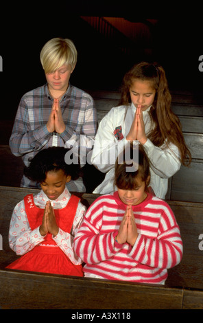 Multiethnic youths age 10 through 14 praying in church. St Paul Minnesota USA Stock Photo