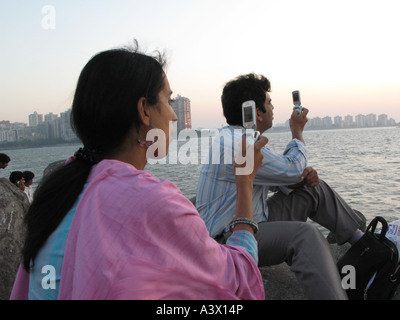 INDIA Hindu couple with mobile phones photographing sunset Mumbai Photo Julio Etchart Stock Photo