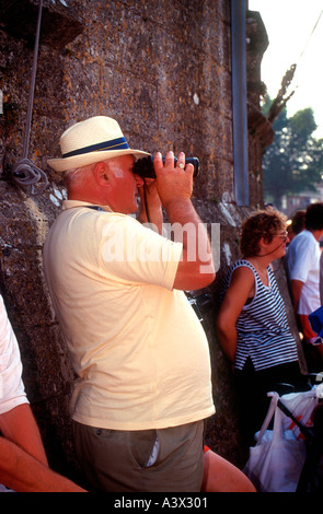 Man with binoculars watches yacht racing Cowes Week sailing regatta Isle of Wight England Stock Photo