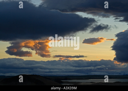 View across Myvatn at dusk towards snow topped hills Clouds lit by setting sun Iceland Stock Photo