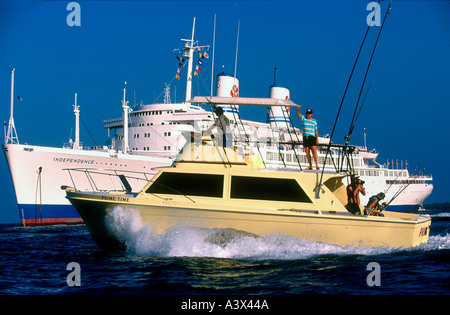 Big game fishing boat passes inter island cruise ship Kona Big Island Hawaii USA Stock Photo