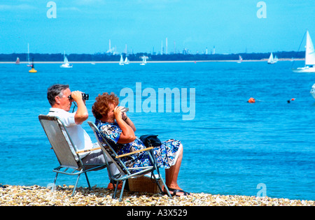 Couple with binoculars watch yacht racing Cowes Week regatta Isle of Wight England Stock Photo