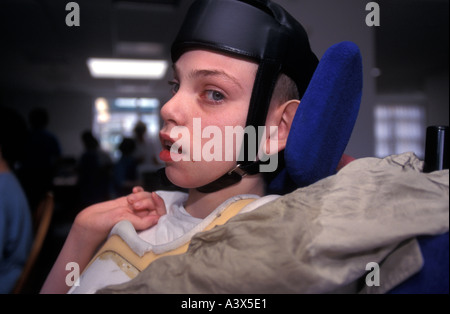 Young autistic boy in wheelchair wearing protective head gear at a special school London UK Stock Photo