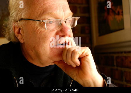 Older man with glasses looking out of a window and thinking Stock Photo