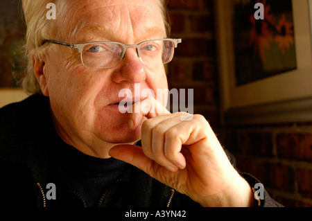 Older man with glasses looking out of a window and thinking Stock Photo