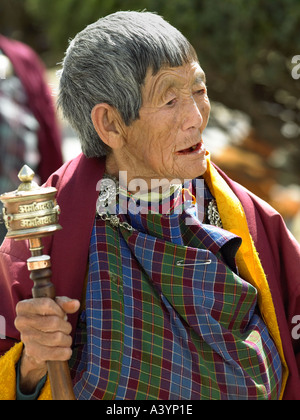 Elderly Bhutanese woman using a prayer wheel circumambulates around the Kings Memorial Chorten in Thimpu Bhutan Stock Photo