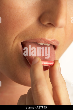 ATTRACTIVE HEALTHY YOUNG WOMAN PLACING PILL ON END OF HER TONGUE Stock Photo