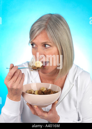 Mature Woman Eating Cereal with Banana Model Released Stock Photo