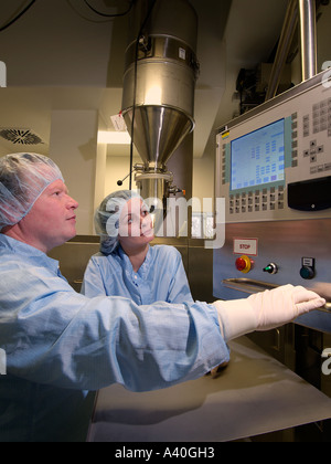 Experienced male industry worker helping teaching female novice coworker with control equipment in clean environment Stock Photo