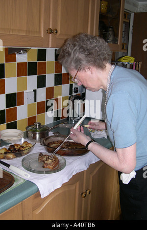 Senior Female serving up a meal for herself and her aging husband Stock Photo