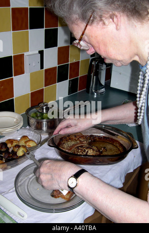 Senior Female serving up a meal for herself and her aging husband Stock Photo