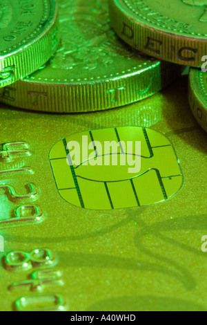 Pound coins on a chip and pin gold credit card, showing the chip, lit green Stock Photo