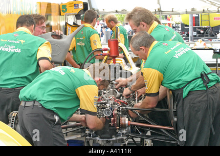 team of mechanics working on racing car in garage area Stock Photo