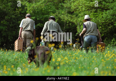 England Devon Fly fishermen carry their rods through the geen fields of the village of Lifton Stock Photo