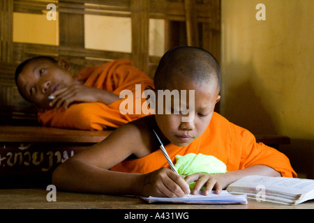 Novice Monk Smoking, another Studying at the Wat Kang School Vang Vieng Laos Stock Photo