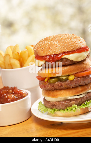 TRIPLE BEEF BURGER WITH CHEESE RELISH PICKLE SALAD ONION RELISH AND CHIPS Stock Photo