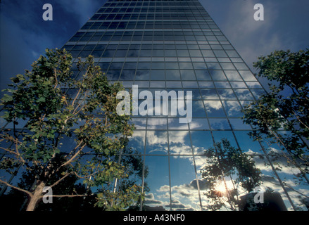 The mirror surface of a glass office building in suburban Irvine California reflects both a sunset and the surrounding foliage Stock Photo