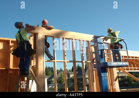 Construction - Worker On Cherry Picker (Lift) And Other Workers Attach Wood Beam To Top of Supports Stock Photo