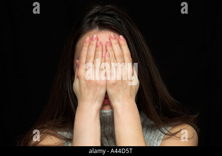 Young woman covering face with hands Stock Photo