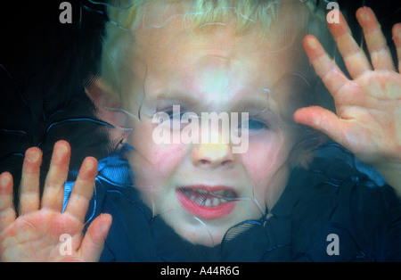 A Little Boy Looking Through Patterned Glass ,In A Door Window. Stock Photo