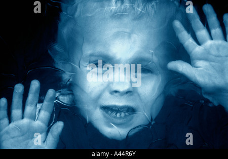 A Little Boy Looking Through Patterned Glass ,In A Door Window. Stock Photo