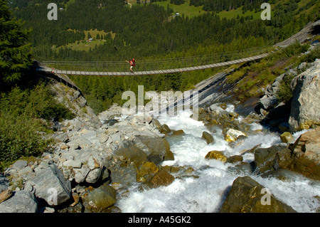 Person walks over suspension bridge near Bionnassay Haute-Savoie France Stock Photo