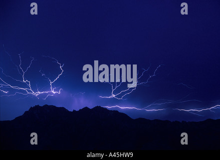 Lightning  strikes against a dark blue sky over the silhouette of mountains in Southern Arizona USA. Stock Photo