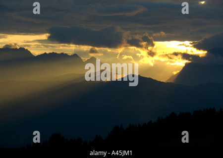 Evening sky yellow sunrays shine through dark skies Haute-Savoie France Stock Photo
