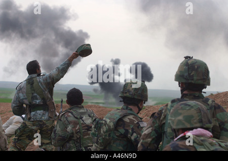 A Kurdish peshmerga fighter waves as US Special forces soldiers watch an airstrike on Iraqi Army forces in Kurdistan Stock Photo